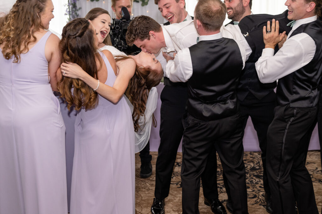 Husband and wife kissing with bridal party